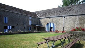 Ein Innenhof mit Steingebäuden, einem Picknicktisch und einer blau-weiß gestreiften Tür.