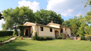 A two-story house with a tiled roof, a front porch, and a staircase leading to the upper floor. - Romantic Hideaway in Lazio (Selci)