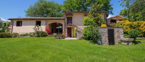 Una casa de dos pisos con entrada de piedra, un pequeño porche con plantas en macetas y un césped bien cuidado.