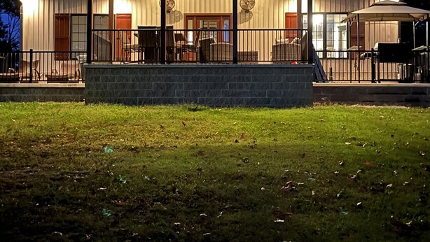 Un bâtiment doté d’un patio couvert, de grandes fenêtres et d’une base en pierre.