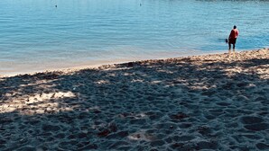 Une plage où l’on voit une personne debout au bord de l’eau.