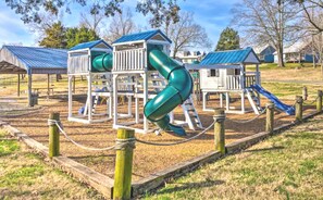 Un parque infantil con diversas estructuras de juego, como toboganes y zonas de escalada, rodeado por una cerca.