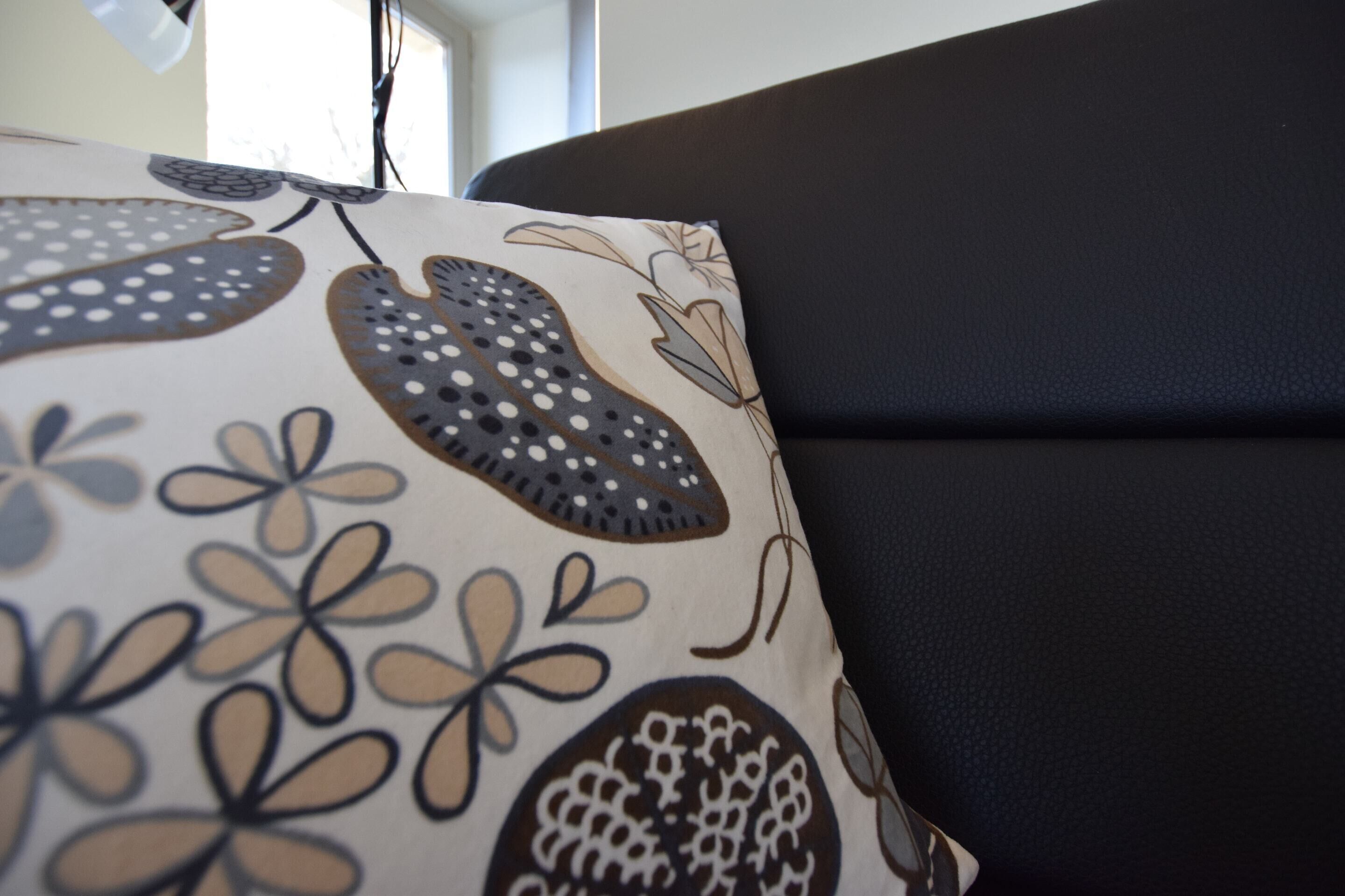 A close-up of a patterned pillow on a black sofa.