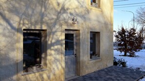 Un bâtiment à deux étages, doté d’un toit plat, d’une porte et de deux fenêtres ornées de jardinières.
