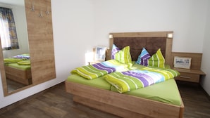 Een slaapkamer met een houten bed, een grote spiegel en een nachtkastje met een lamp.
