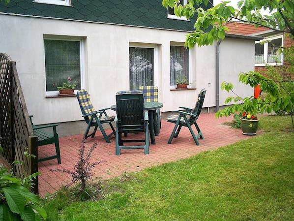 A patio area with a table and chairs, potted plants, and a wooden fence.