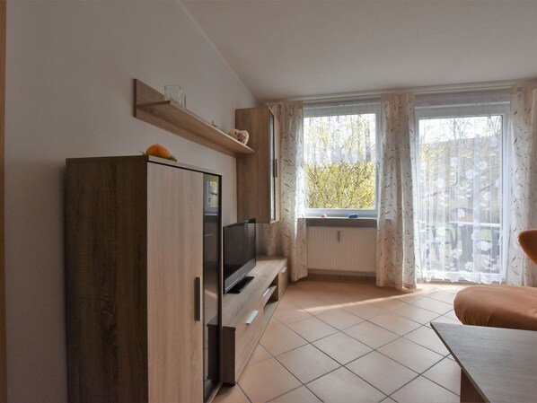A modern kitchen with a built-in oven, a wooden cabinet, and a window with curtains.
