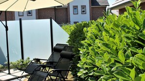 Eine Terrasse mit Sitzgelegenheiten und einem großen Sonnenschirm.