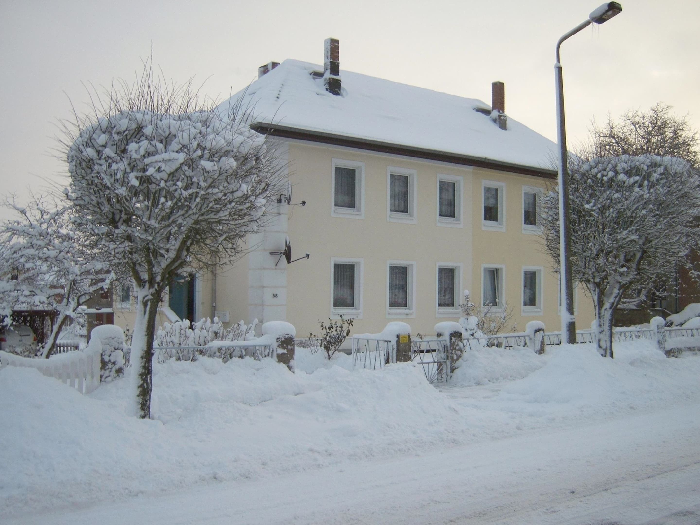 A multi-story building with a snow-covered roof and a street lamp in front.