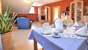 A dining area with a table set for four, a sofa, and a potted plant. - Quiet Apartment in Merlsheim With Balcony (Nieheim)