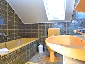 A bathroom with a bathtub, a sink, and a toilet. There is a skylight above the bathtub, and the walls are tiled with a patterned design. - Quiet Apartment in Merlsheim With Balcony (Nieheim)