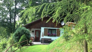 A wooden chalet with a sloped roof, a front porch, and a small garden area. - Engenstein Woodland Escape (Schleusegrund)