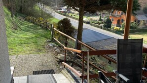 A balcony with a view of a road, a grassy area, and a building with a red roof. - Engenstein Woodland Escape (Schleusegrund)