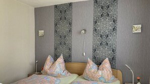 A double bed with patterned pillows, a bedside table with a lamp, and a wall with vertical patterned panels. - Engenstein Woodland Escape (Schleusegrund)