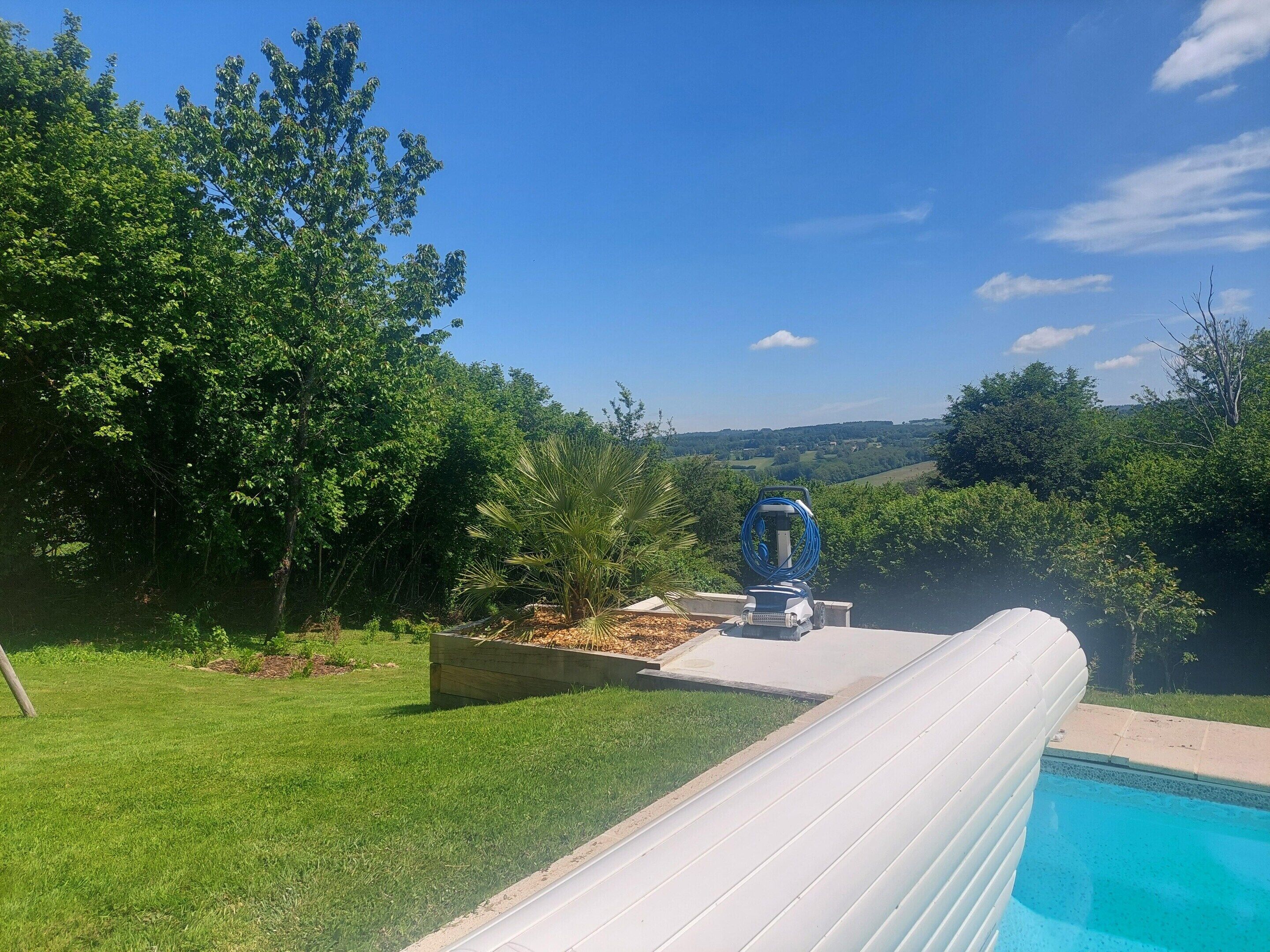 Una piscina con vistas despejadas del paisaje circundante, un carretel de manguera y una jardinera de madera.