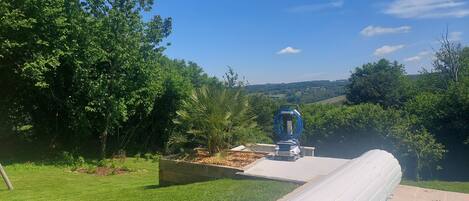 Una piscina con vistas despejadas del paisaje circundante, un carretel de manguera y una jardinera de madera.