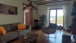 Una sala de estar con sofá, sillón, mesa de centro y lámpara colgante.