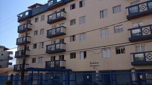 Un edificio residencial de varios pisos con balcones, una verja azul y un número de calle visible.