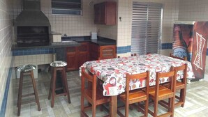 Una cocina con salpicadero de azulejos, horno empotrado, una mesa con sillas y un refrigerador Budweiser.