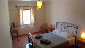 Une chambre à coucher avec un lit, un bureau, une chaise et une fenêtre avec des rideaux.