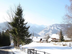 A snow-covered landscape with a church, mountains, and a wooden fence.