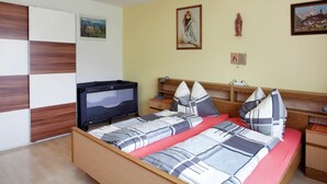 Quarto com cama, televisão, mesa de cabeceira e parede com três quadros.