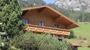A wooden chalet with a sloped roof, two windows, and a balcony. It is surrounded by greenery and mountains in the background. - Chalet in Grossarl With Sauna Near ski Area (Grossarl)