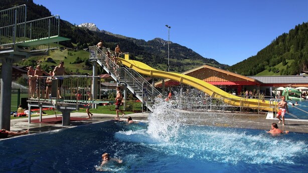 A swimming pool with a water slide, surrounded by mountains. - Chalet in Grossarl With Sauna Near ski Area (Grossarl)