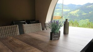 A dining table with a rustic wooden finish, surrounded by wicker chairs. A small potted lavender plant is placed on the table, and a cylindrical vase is visible in the background. - Chalet in Grossarl With Sauna Near ski Area (Grossarl)