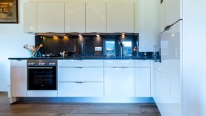 Eine moderne Küche mit weißen Schränken, einer schwarzen Arbeitsplatte und einem eingebauten Backofen.