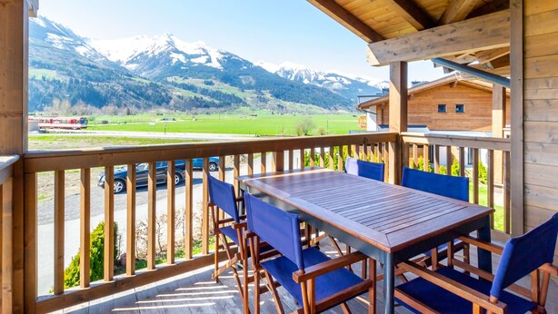 Eine Holzterrasse mit Tisch und Stühlen, mit Blick auf eine Berglandschaft.