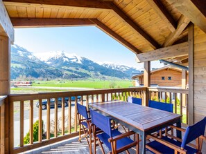 Una terraza de madera con mesa y sillas, con vista a un paisaje montañoso.