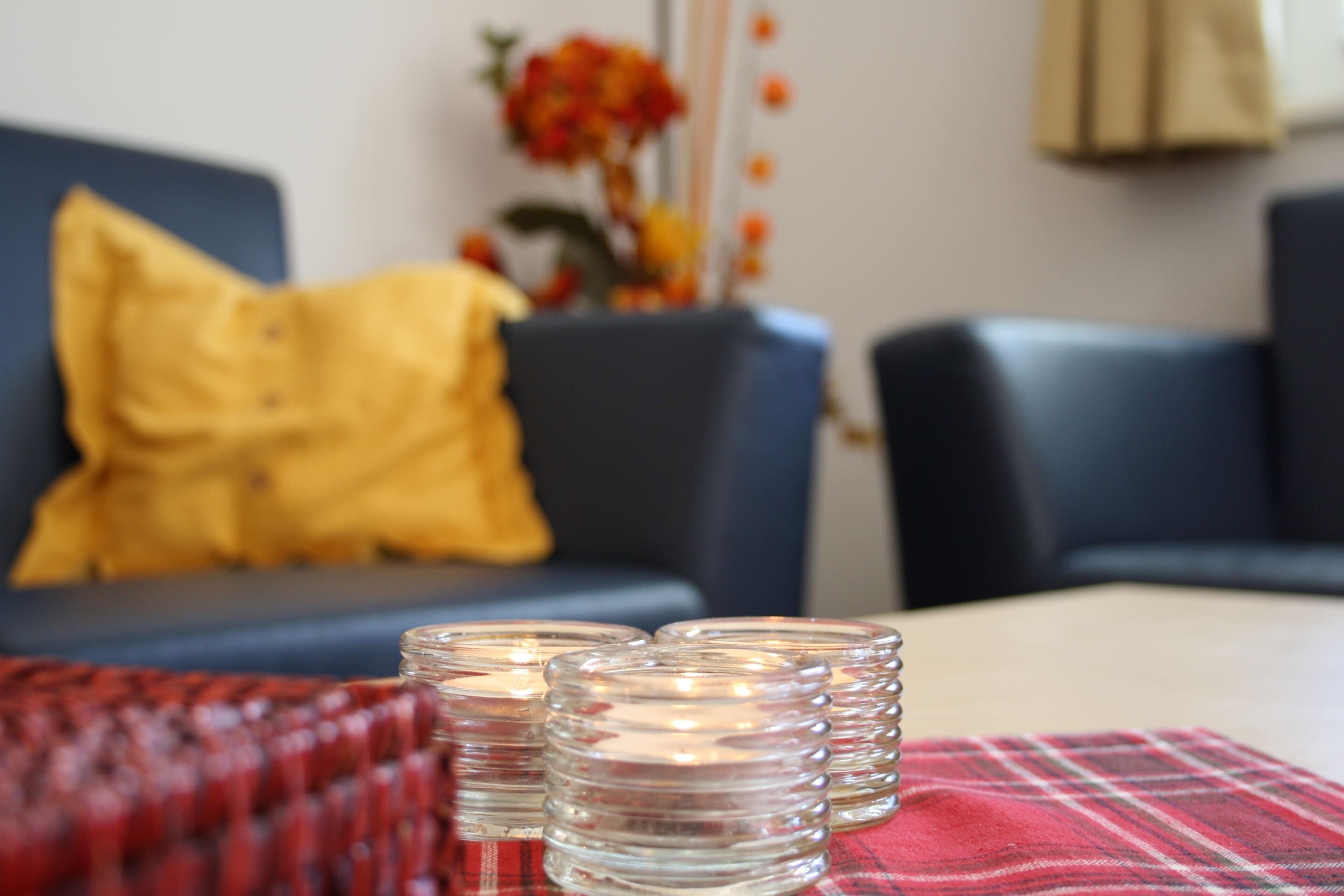 Une table avec des chandeliers en verre transparent et une nappe à carreaux rouges.