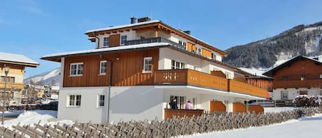 A multi-story building with wooden balconies and a snow-covered ground.