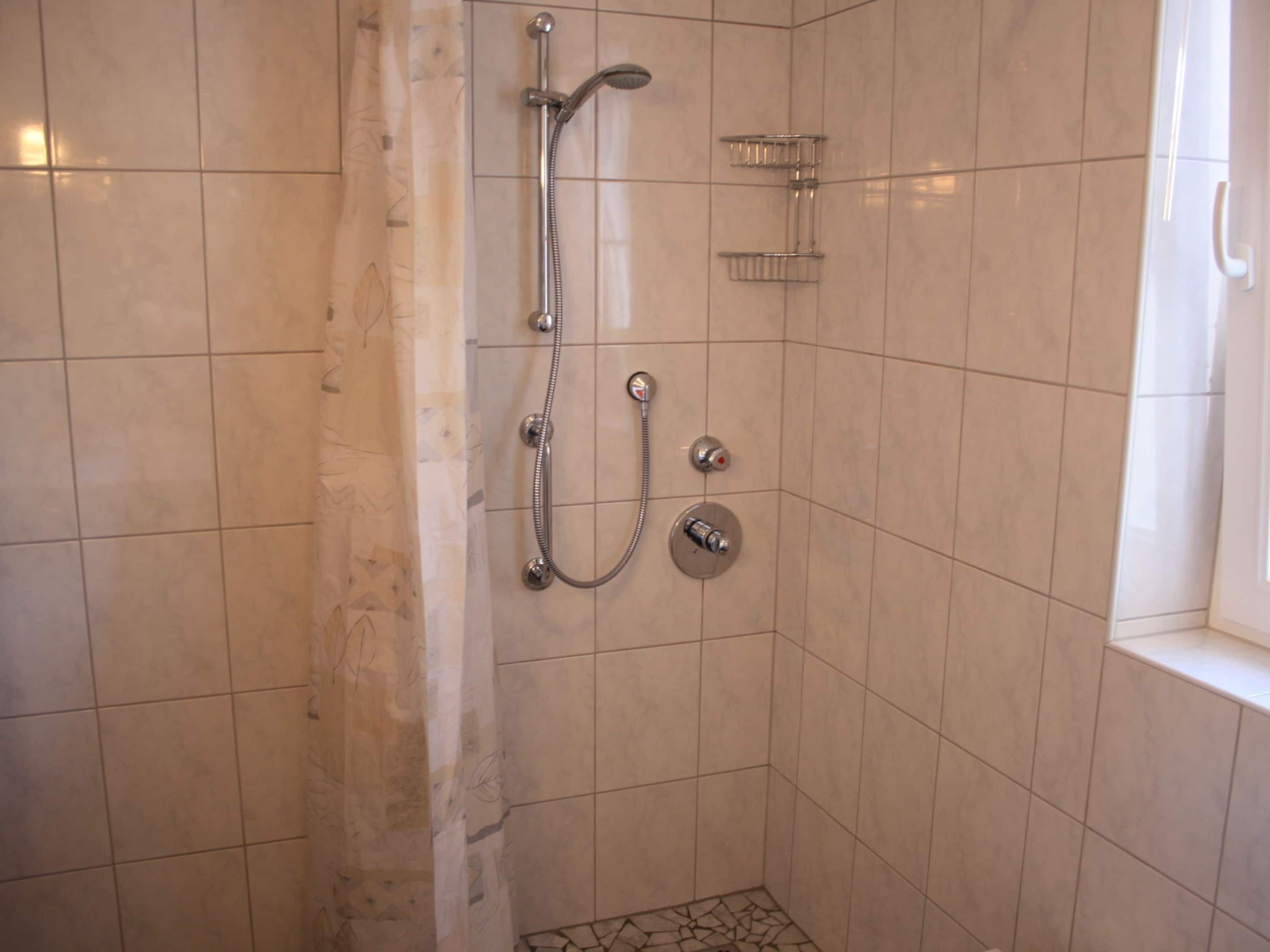 Una ducha con cabezal de ducha de mano y grifo empotrado.