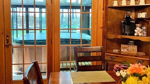 Ein Holzinnenraum mit Essbereich, einer Kaffeestation und Blick durch große Fenster.