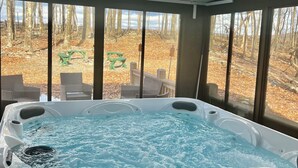 Ein Whirlpool mit Blick auf ein bewaldetes Gebiet durch große Fenster.