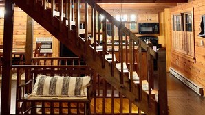 Ein Holzinnenraum mit einer zentralen Treppe, Holzwänden und einem Essbereich mit Tischen und Stühlen.