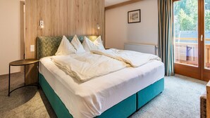 A bedroom with a bed, a nightstand, a window with curtains, and a radiator. - Apartment in Wald Near Zillertal Ski Area (Wald im Pinzgau)