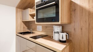 A compact kitchen with a built-in oven, a coffee maker, and a sink. - Apartment in Wald Near Zillertal Ski Area (Wald im Pinzgau)