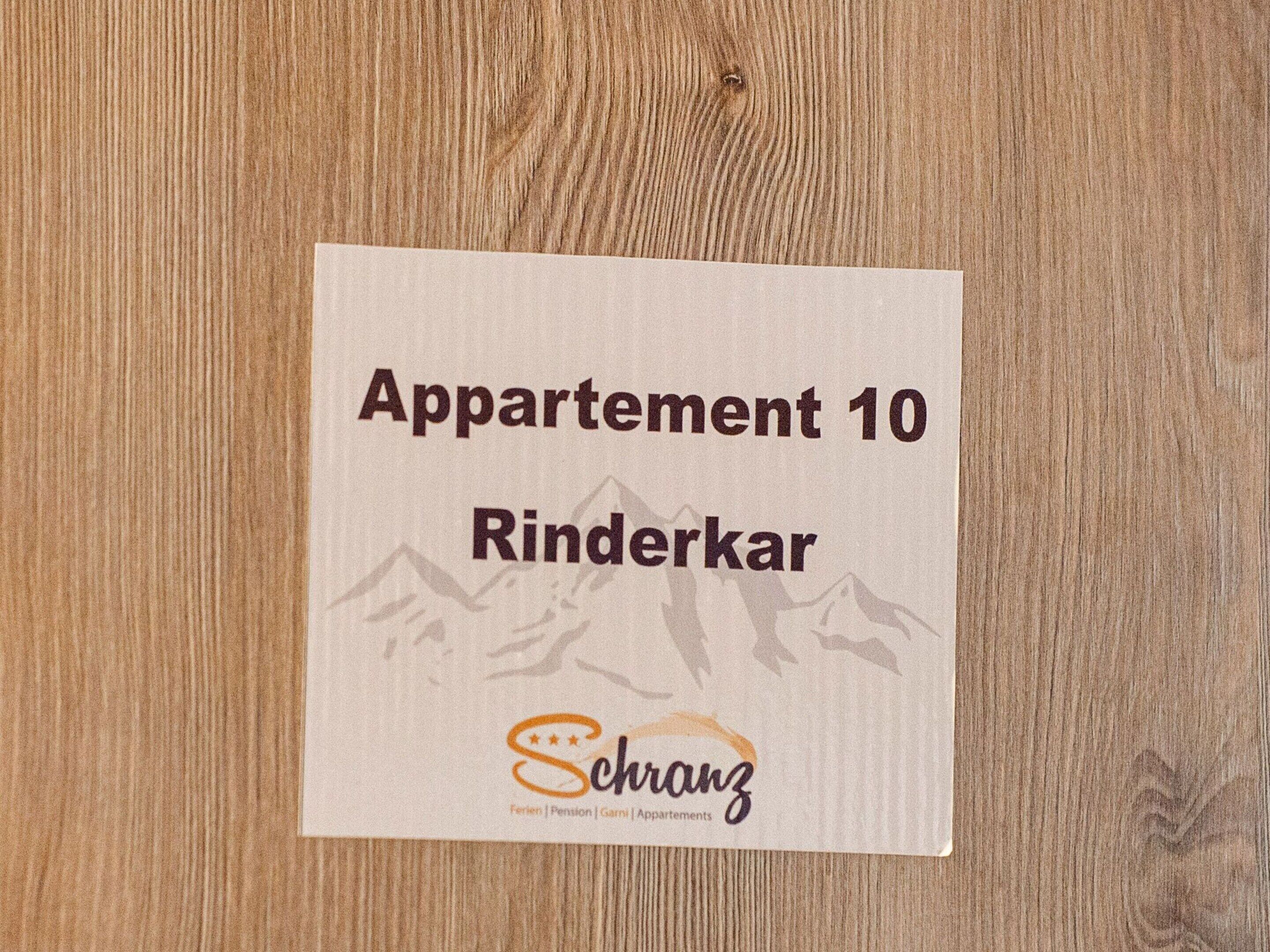 A sign for 'Apartment 10 Rinderkar' with a mountain silhouette and the Schranz logo.