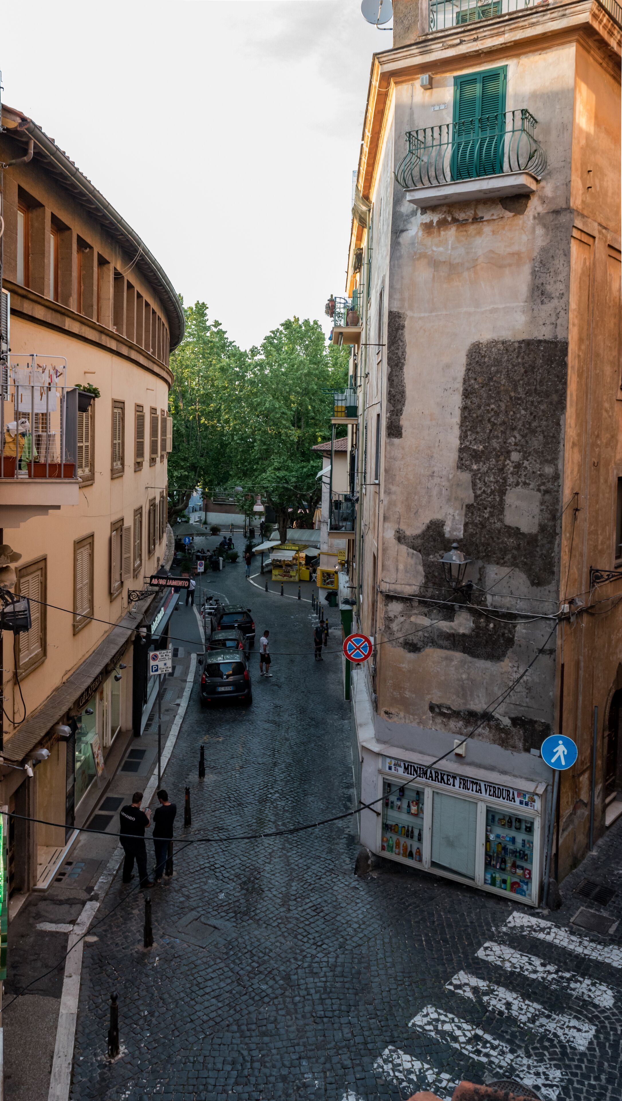 Una estrecha calle adoquinada bordeada de edificios, un paso de peatones y una tienda con un letrero.
