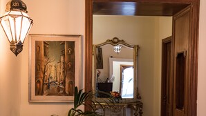 Un couloir avec une plante en pot, un tableau encadré, un miroir et une porte en bois.