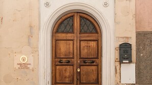 Une porte à deux battants en bois, ornée d’un panneau de verre, encadrée par un arc en pierre, au-dessus d’une entrée pavée.