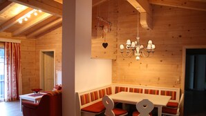 A cozy wooden interior with a dining table, benches, and a red sofa. - Chalet in Leogang Near Ski Slopes (Leogang)