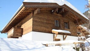A wooden chalet with a sloped roof, wooden balcony, and snow-covered surroundings. - Chalet in Leogang Near Ski Slopes (Leogang)