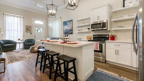 Una cocina moderna con armarios blancos, electrodomésticos de acero inoxidable y una isla central con taburetes.