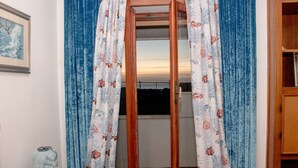 Une pièce avec une armoire en bois, un tableau encadré au mur et une fenêtre avec des rideaux.