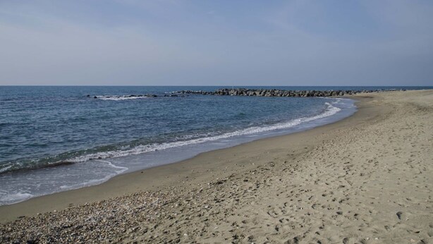 Une plage avec un rivage rocheux et des vagues calmes.