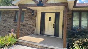 A house with a brick exterior, a front porch with a wooden beam structure, a white door, and a small window to the left. - Breathtaking Lake View w/Pool Nearby!- Knoxville/Oak Ridge (Knoxville)